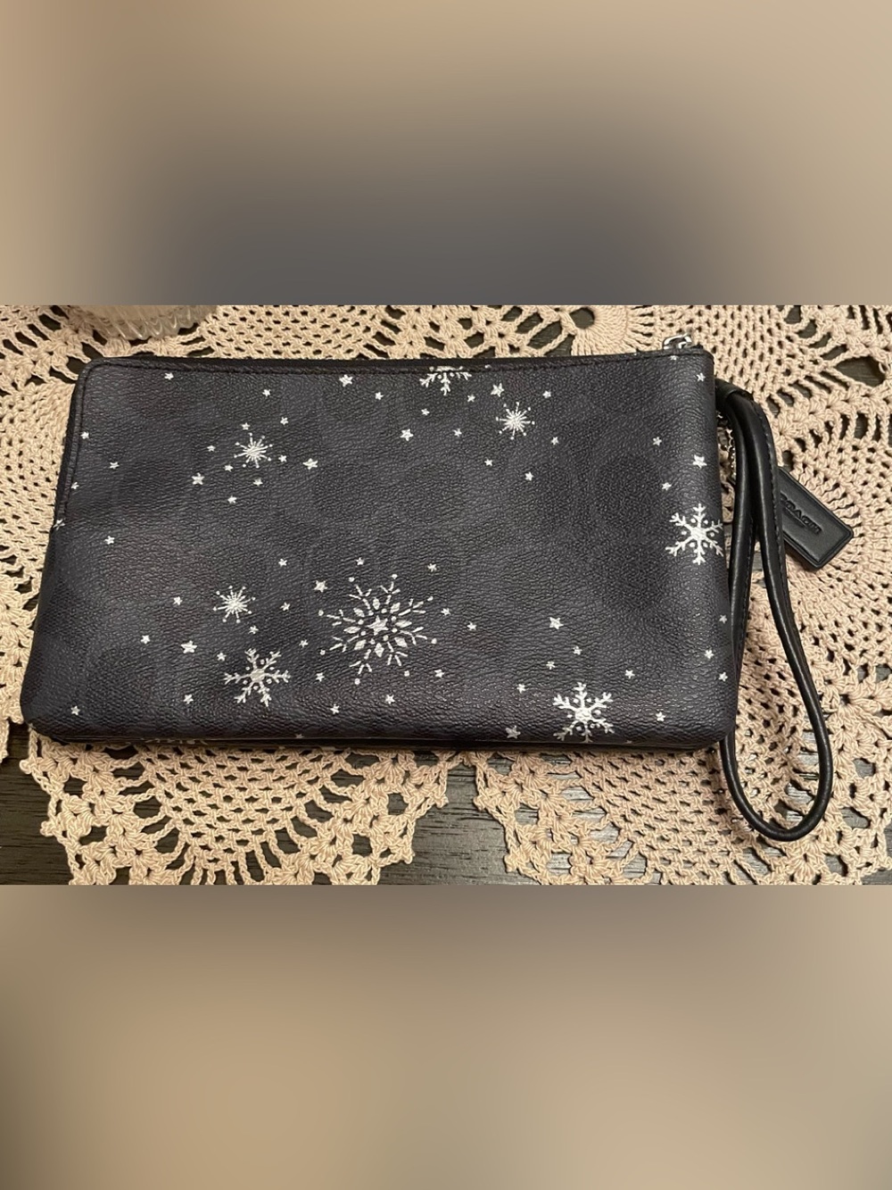 Coach corner zip wristlet decorated with a silver snowflake and star print